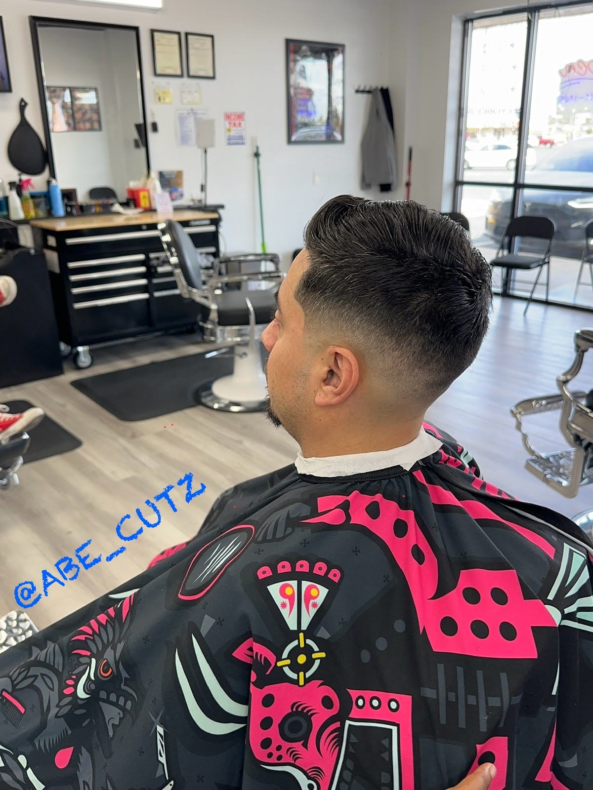 Clean low taper fade with styled top, barber shop background
