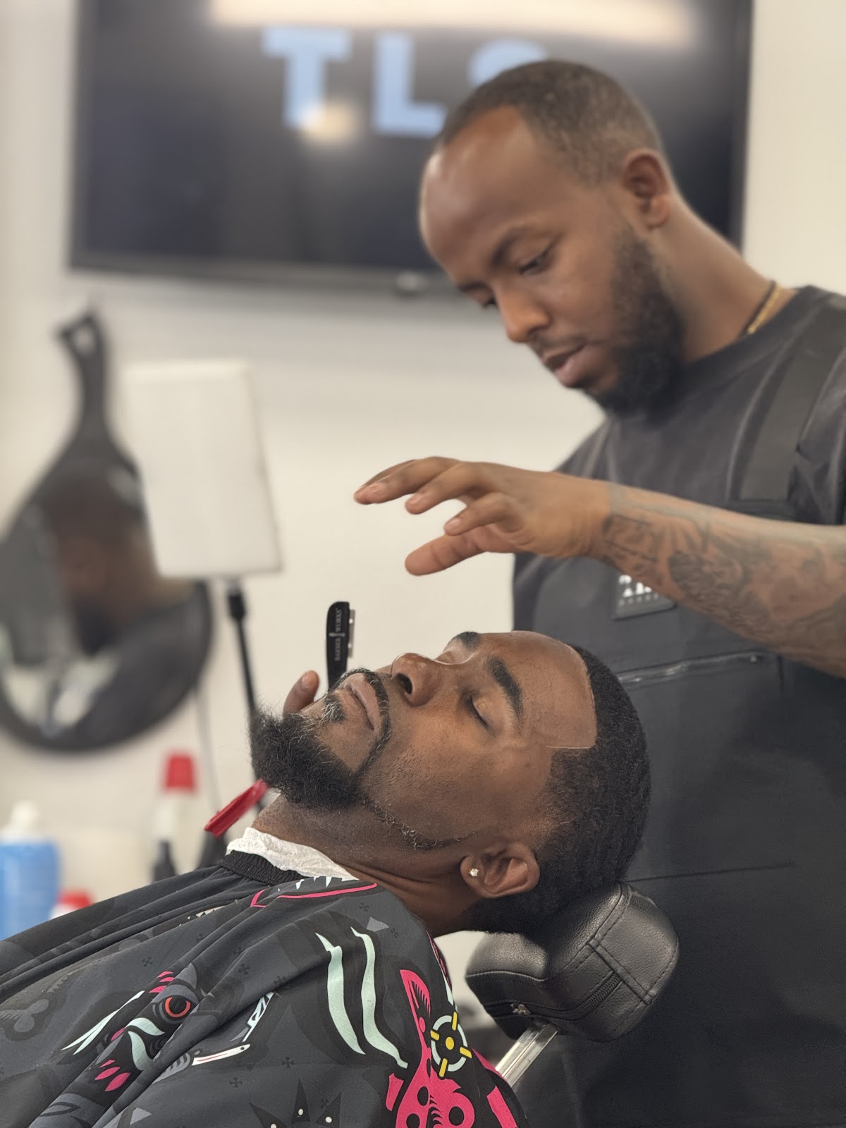 Barber performing straight razor beard trim on client in chair